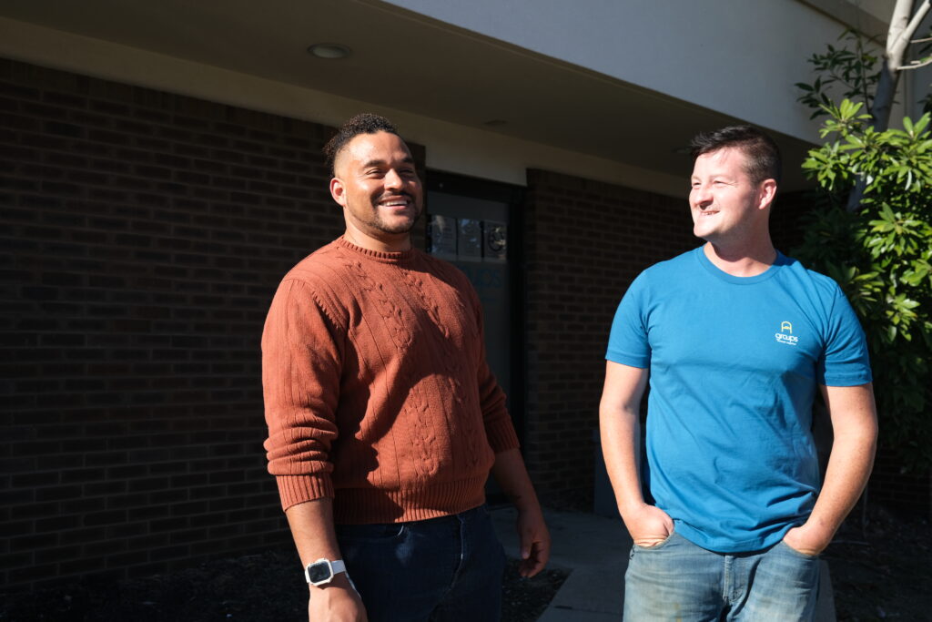 Two men standing in front of a building laughing